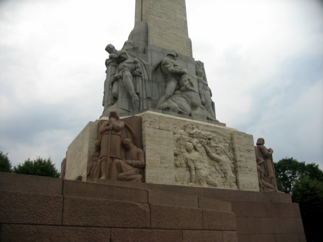 Dolní část pomníku zdobí ze všech stran sousoší a reliéfy, které zobrazují události z lotyšské historie a symbolicky i některé prvky lotyšské kultury.