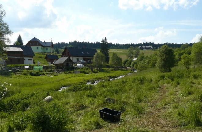 Malebná krajina Kvildy s pastvinou pro ovce v popředí.