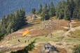 Již z výstupu na vrcholek se otevírá krásný pohled na horskou louku, kde mají základnu vyznavači paraglidingu. Vzdušné proudy zde pro ně vytváří ideální podmínky a tak jejich padákové kluzáky, jak zní správný název křídla, nepřetržitě krouží nedaleko od nás.