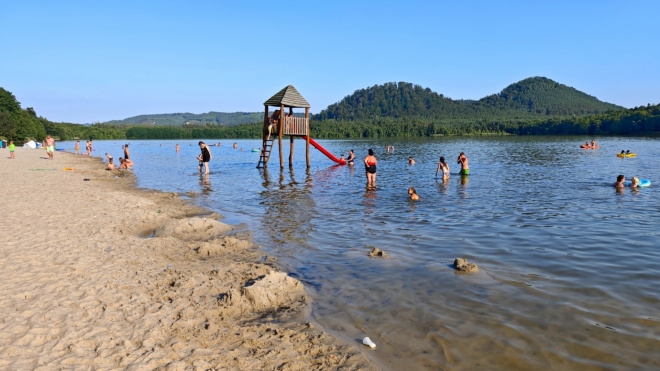 Hamerské jezero je v neděli večer stále plné. Vedro nepolevuje. V pozadí děvín a Ostrý.